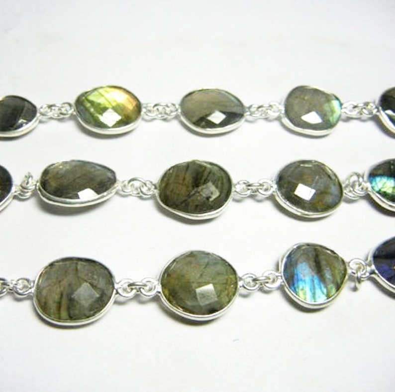 May include: A silver chain necklace with oval-shaped labradorite gemstones. The stones have a iridescent sheen with shades of green, blue, and gold.