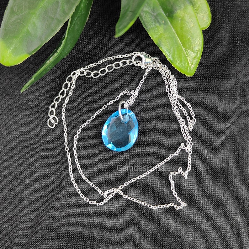 May include: A silver chain necklace with a light blue crystal pendant.
