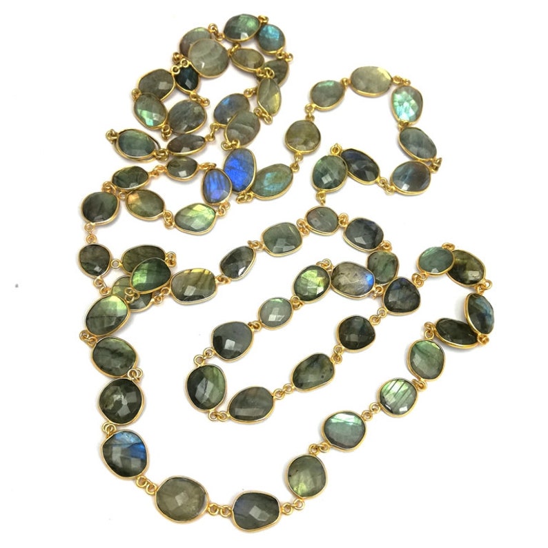 May include: A long gold chain necklace with oval-shaped labradorite gemstones. The stones are a mix of green, blue, and gray with iridescent flashes.