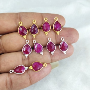 Pode incluir: Uma coleção de dez pingentes de rubi com detalhes em ouro e prata. Os pingentes têm a forma de uma lágrima e são facetados.