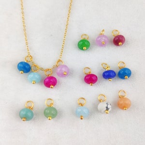 Puede incluir: Un collar de cadena dorada con múltiples cuentas de piedras preciosas de colores. El collar tiene una variedad de cuentas en tonos de azul, verde, rosa y blanco. Las cuentas son todas redondas y tienen un acabado liso y pulido.