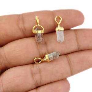 May include: Three gold-plated crystal point pendants. Each pendant features a clear quartz crystal point with a gold-plated bail.