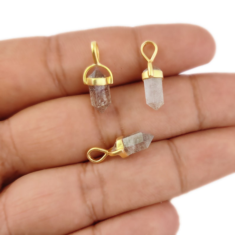 May include: Three gold-plated crystal point pendants. Each pendant features a clear quartz crystal point with a gold-plated bail.