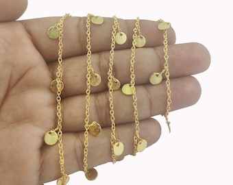 May include: A gold chain necklace with small, round, gold charms hanging from it. The chain is delicate and the charms are evenly spaced.