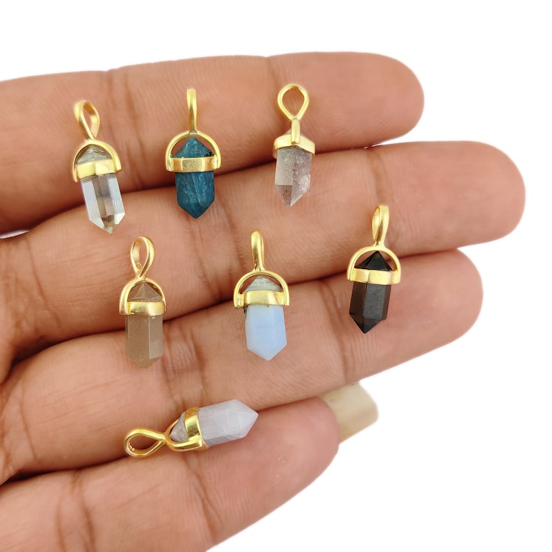 May include: Eight gold-plated crystal point pendants in a variety of colours, including clear, blue, brown, and black.