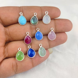 以下が含まれることがあります： シルバー製のベイルが付いた、10種類の宝石の雫型のチャームの詰め合わせ。チャームは、青、緑、ピンク、赤、白など、さまざまな色があります。