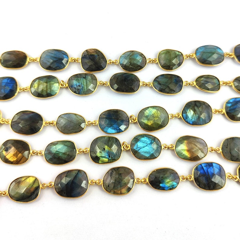 May include: A strand of gold-toned chain with oval-shaped labradorite gemstones. The stones are a mix of dark blue, green, and gold.