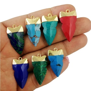 May include: Eight gold-tipped arrowhead pendants with different colored stone inlays. The stones are turquoise, green, blue, and red.