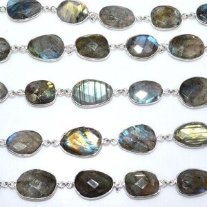 May include: A strand of silver chain with oval-shaped labradorite gemstones. The stones are a mix of green, blue, and gold.