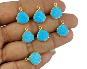 May include: Eight turquoise blue gemstone pendants with gold-tone metal settings. Each pendant features a carved floral design and a loop for attaching a chain or cord.