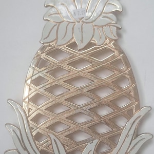 May include: A decorative pineapple-shaped object with a gold-colored body and white accents. The pineapple design features a diamond-patterned body and white leaves. The price tag shows $2.99.