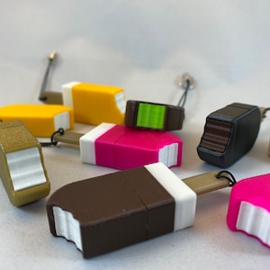 Könnte beinhalten: Eine Sammlung von acht bunten USB-Sticks in Form von Eis am Stiel mit verschiedenen farbigen Oberteilen und weißen Unterteilen. Die Sticks sind aus Kunststoff und haben oben ein kleines Loch zum Anbringen eines Schlüsselanhängers.