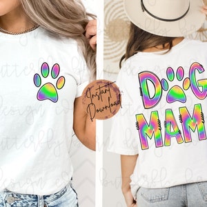 May include: Two white t-shirts with a tie-dye design. One shirt has a rainbow paw print and the other says "Dog Mama" with a rainbow paw print in the middle of the word "Dog".