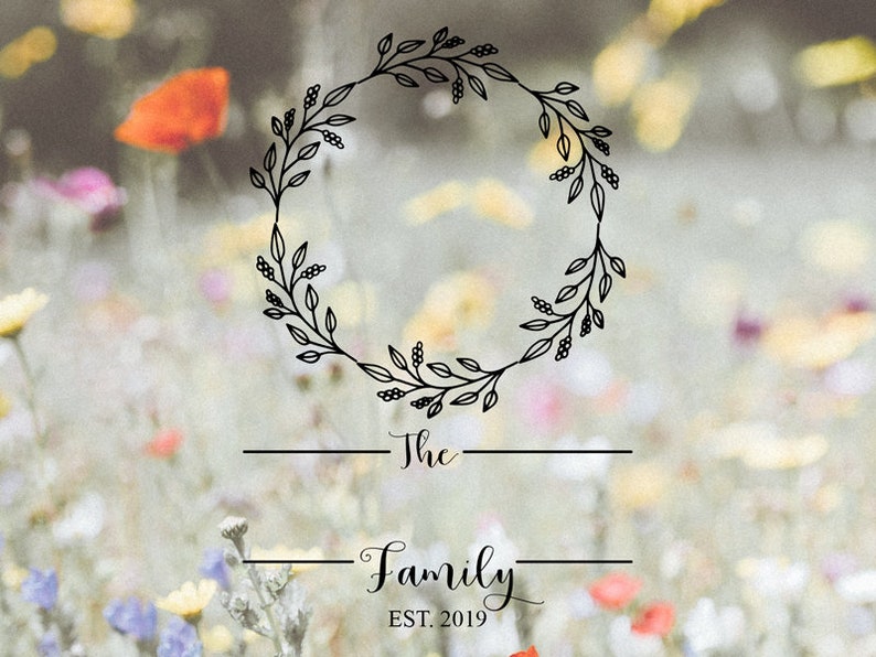 Peut inclure: Une couronne florale noire avec le texte "The Family EST. 2019" sur un fond flou de fleurs color&eacute;es.