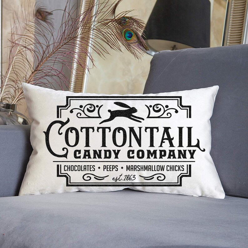 May include: White pillow with a black and white logo that says "Cottontail Candy Company" with a bunny rabbit graphic and the text "Chocolates, Peeps, Marshmallow Chicks, est. 1863."