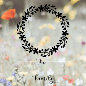 Op de afbeelding: Een zwarte bloemenkrans met de tekst "The Family" eronder. De krans is geplaatst tegen een wazige achtergrond van een bloemenveld.