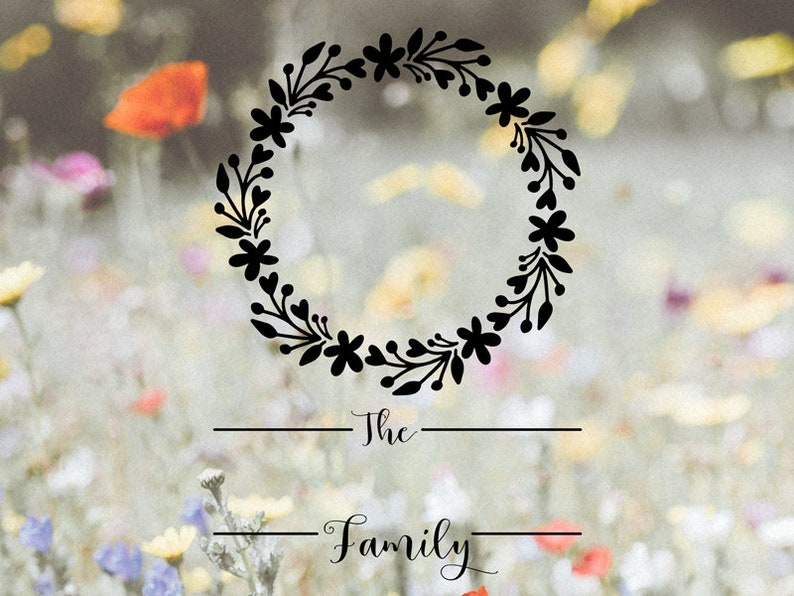 Op de afbeelding: Een zwarte bloemenkrans met de tekst "The Family" eronder. De krans is geplaatst tegen een wazige achtergrond van een bloemenveld.