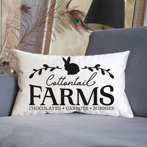 May include: White throw pillow with black text and a silhouette of a rabbit. The text reads "Cottontail Farms Chocolates Carrots Bunnies".