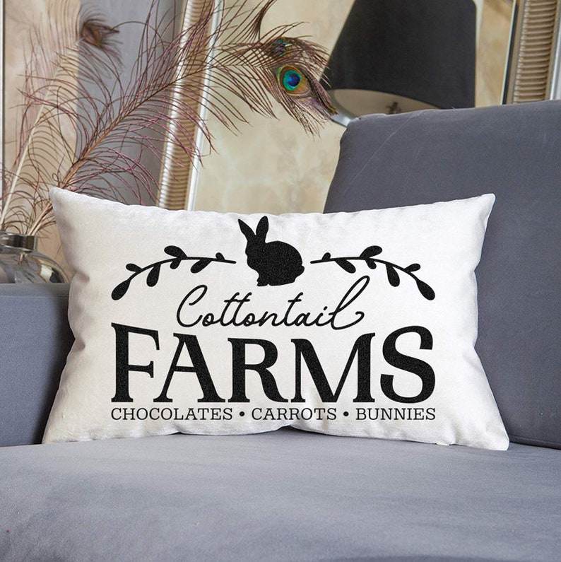 May include: White throw pillow with black text and a silhouette of a rabbit. The text reads "Cottontail Farms Chocolates Carrots Bunnies".