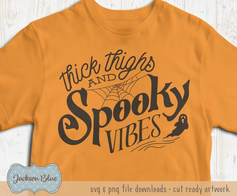 Puede incluir: Camiseta naranja con texto negro que dice "thick thighs and spooky vibes" con un gr&aacute;fico de telara&ntilde;a y fantasma.