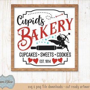 May include: A white sign with a brown wooden frame, featuring the text "Cupid's Bakery" in red and black lettering. The sign also includes a silhouette of Cupid with an arrow, a rolling pin, and the text "Cupcakes Sweets Cookies Est. 1814".