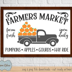 May include: A white sign with brown wood frame advertising a Farmers Market. The sign features a black silhouette of a pickup truck with a bed full of orange pumpkins. The text on the sign reads "FARMERS MARKET", "farm fresh", "open daily", "PUMPKINS APPLES GOURDS HAY RIDE".