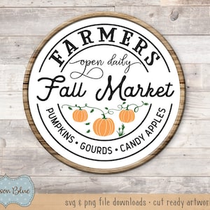 May include: A white circle with a brown wooden frame, featuring the text "FARMERS open daily Fall Market PUMPKINS GOURDS CANDY APPLES". The circle has a design of three orange pumpkins with green vines and leaves.