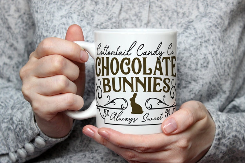 May include: White ceramic mug with a brown graphic that says "Cottontail Candy Co. Chocolate Bunnies 5&cent; Always Sweet 5&cent;". The graphic features a stylized bunny silhouette.