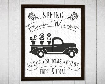 May include: Black and white illustration of a pickup truck with flowers in the bed. The text "Spring Flower Market" is above the truck and "Seeds - Blooms - Bulbs Fresh & Local" is below the truck.