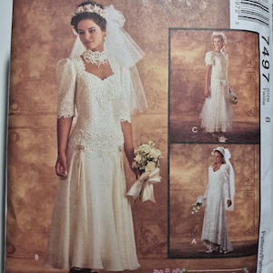 May include: A vintage McCall's sewing pattern for a wedding dress. The pattern is for size 8 and features a lace bodice and a flowing skirt. The pattern is called "Alicyn Exclusives" and has a barcode on the back.