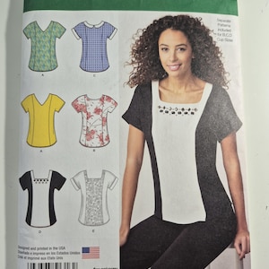 May include: Simplicity sewing pattern 1316 for a top with various sleeve and neckline options. The envelope displays illustrations of five different top designs in green, blue, yellow, floral, and black and white, plus a photo of a black and white top.