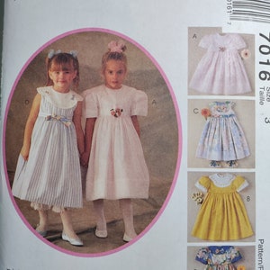 May include: A sewing pattern for a girl's dress. The pattern includes four different styles of dresses, all with a vintage look. The pattern is for sizes 3-6.