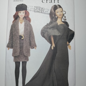May include: A vintage Vogue Craft pattern featuring two doll fashions. One doll is dressed in a gray coat and skirt with a black hat, the other in a long black gown. The pattern is labeled "7243" and "Circa 1980".