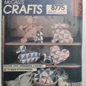 May include: A McCall's Crafts pattern for making patchwork pillows, toys, ornaments, and a sachet. The pattern number is 8775 and the price is $4.25. The pattern shows a variety of patchwork designs, including a bear, a rabbit, a duck, a heart, and a small dog.