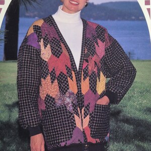 May include: A quilted jacket with a black and white checkered pattern, featuring colorful patchwork in shades of purple, orange, and red. The jacket has a black ribbed collar, cuffs, and hem, and a front zipper. The model is wearing a white turtleneck.