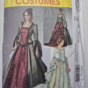 May include: A McCall's Costumes pattern envelope featuring illustrations of three different historical gowns. The gowns are in shades of pink, green, and gray, with intricate lace and trim details. The envelope includes the pattern number M6097 and size information.