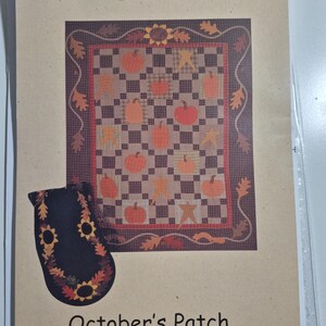 May include: A pattern for a quilt and table runner from Backyard Quilts. The quilt design features pumpkins and stars on a checkered background, with dimensions of 60" x 76". The table runner is 18" x 48". The text "October's Patch..." is visible.