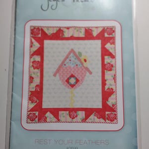 May include: A pink and red quilt pattern with a birdhouse design. The pattern is called "Rest Your Feathers" and is numbered #0699.