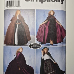 May include: Simplicity pattern 5794 featuring cape designs. The pattern includes various cape styles, with options for different lengths and fabrics. The image shows models wearing capes in brown, burgundy, and green. The pattern size is XS, S, M, and L.