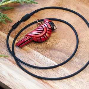 Photo shows 1 bright red mini cardinal mosaic pendant on a black cords with snap closure.
