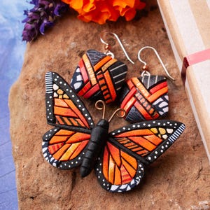 Bright Orange Monarch Butterfly pin on a stone shown with coordinating earrings. Mosaic-style art brooch with bits of shine, texture and warm colors. Front angle