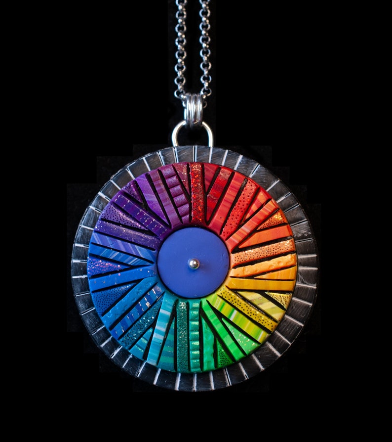 Photo shows mosaic rainbow fidget spinner in bright colors. Spinner hangs from a silver chain.