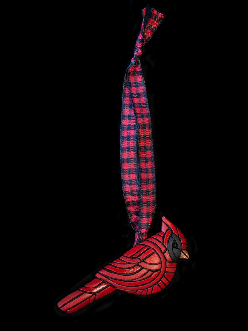 Photo shows bright red cardinal mosaic ornament on a red plaid ribbon.