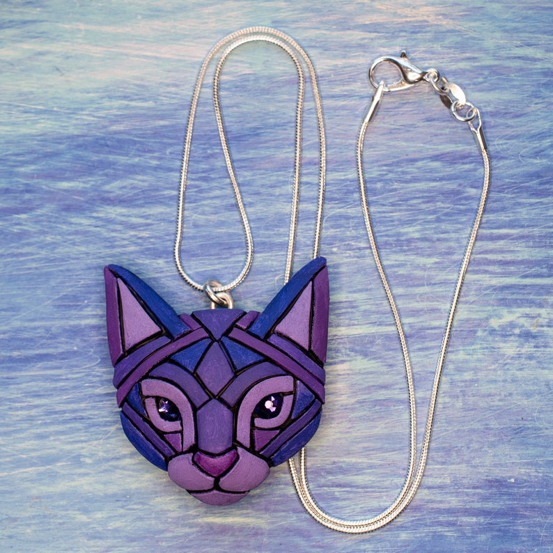 Photo shows purple mosaic cat necklace in a hand. Pendant hangs from a silver snake chain with lobster clasp.