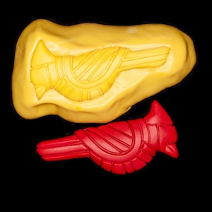 Op de afbeelding: Twee siliconen mallen voor het maken van vogelvormige decoraties. De grotere mal is geel en de kleinere mal is rood.
