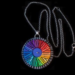 Photo shows mosaic rainbow fidget spinner in bright colors. Spinner hangs from a silver chain with lobster clasp.