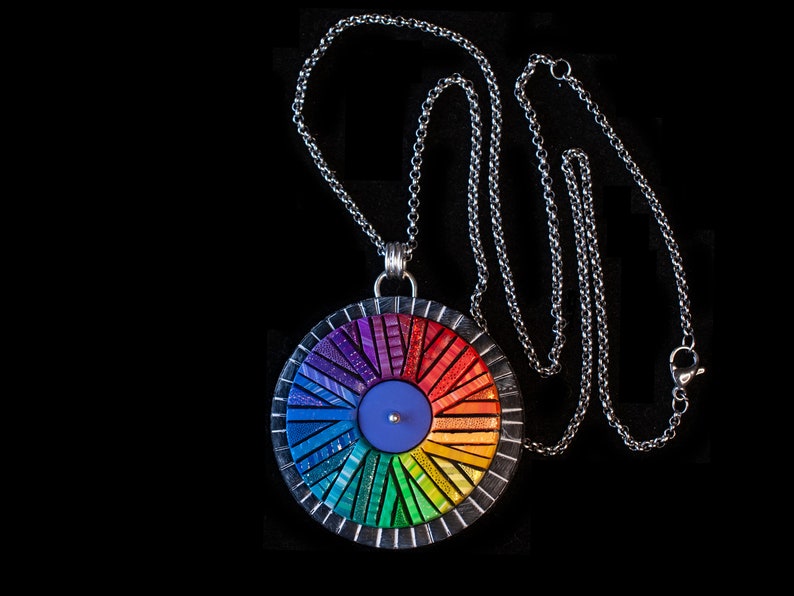 Photo shows mosaic rainbow fidget spinner in bright colors. Spinner hangs from a silver chain with lobster clasp.