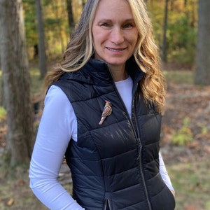 Photo shows model wearing neutral female cardinal on a vest in an outdoor setting.