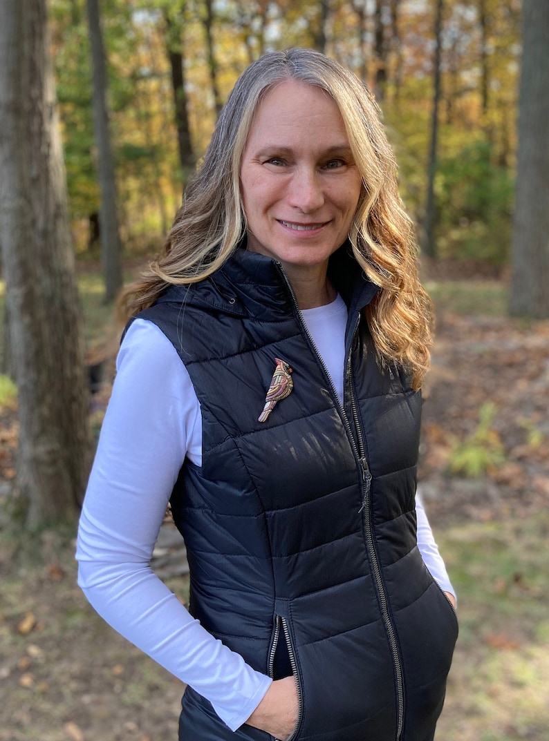 Photo shows model wearing neutral female cardinal on a vest in an outdoor setting.