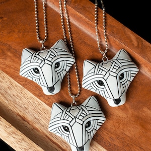 Photo shows group of three white Arctic fox necklaces made in mosaic style from the front view. Pendants hang from silver ball chains. Eyes are sparkling black crystals. Fits in the palm of your hand. Made to look like an ancient amulets.